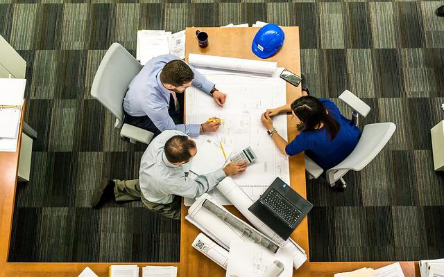 Reunión En Mesa De Trabajo De Dos Hombres Y Una Mujer Con Elementos De Oficina